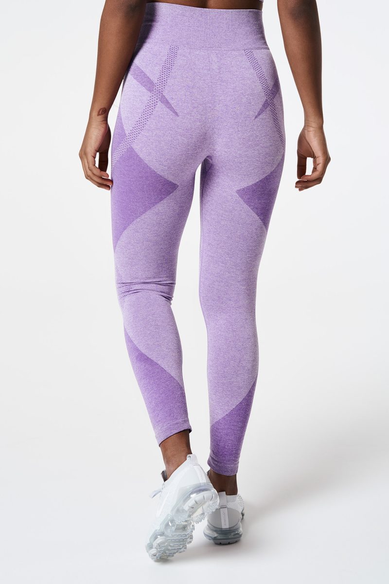 View from behind of a Black woman’s legs standing, wearing Violet Bold Seamless Performance Leggings, showcasing the smooth fit and bold color, emphasizing how they contour perfectly to her shape.