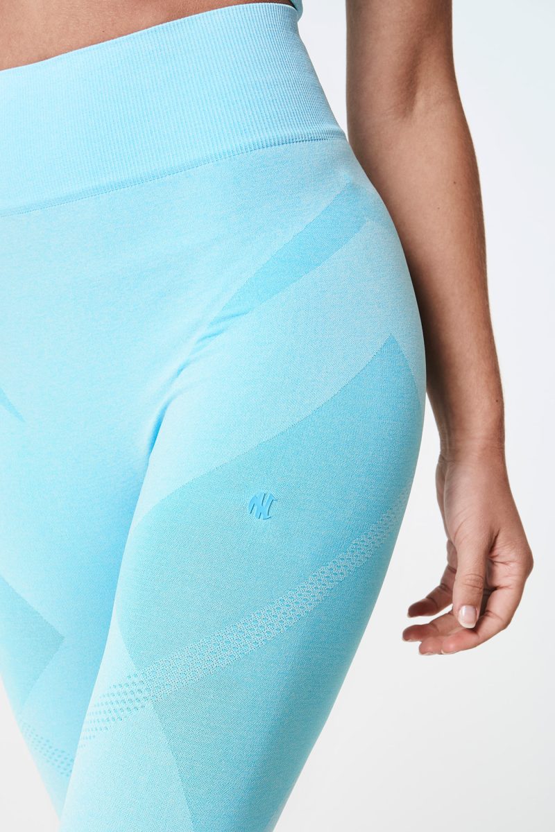 Close-up of the front hip of a blonde woman, wearing Aqua Blue Bold Seamless Performance Leggings, highlighting the contouring fit and vibrant color.