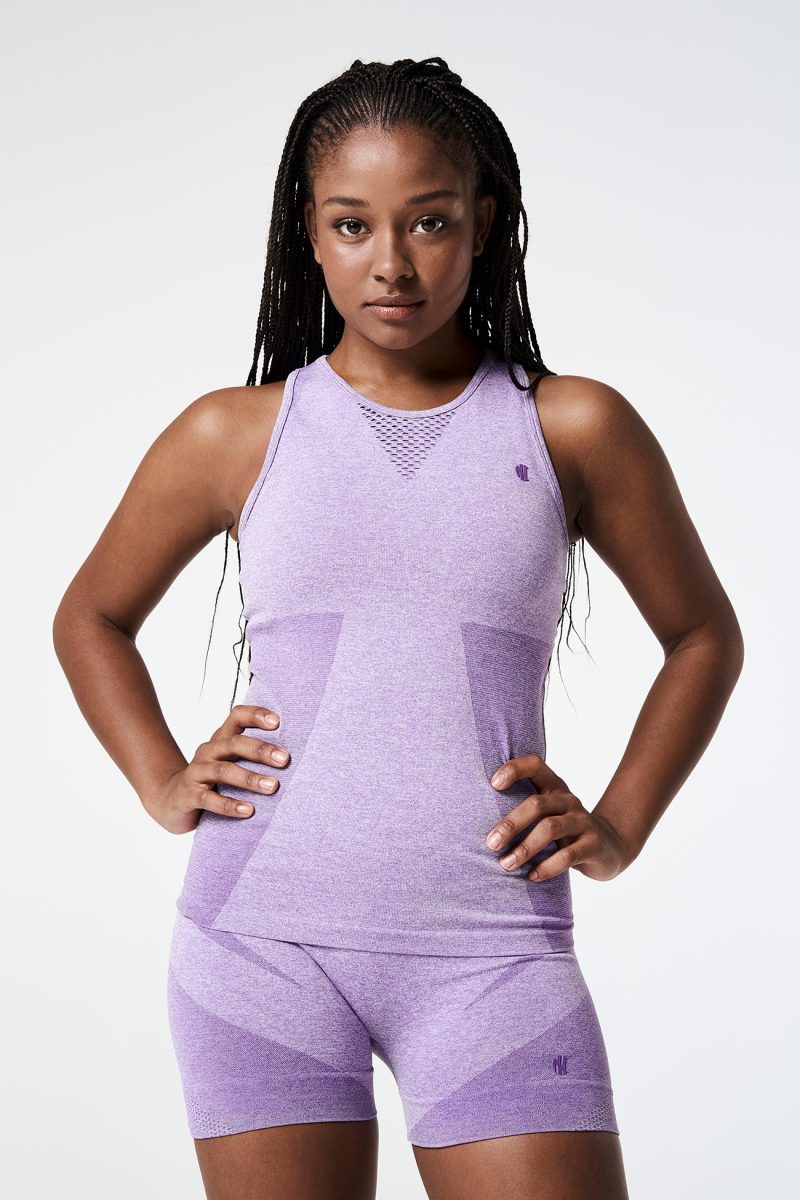 A Black woman confidently posing with her hands on her hips, dressed in a Violet Bold Seamless Performance Tank Top that highlights her athletic style.